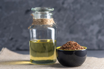 Flax seeds in a pile and linseed golden oil in a glass bottle on the table. Healthy diet with omega 3 fatty acids.