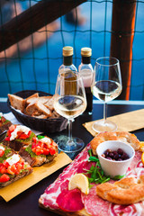 Romantic dinner for two at sunset. White wine and Tasty italian snack: fresh bruschettes  and meat on the board in outdoor cafe with amazing view in Manarola