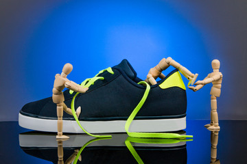 Blue shoe with three wooden puppets on blue background with copy space.