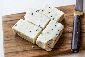 Turkish Feta Cheese with Black Cumin (Sesame) Seeds on Wooden Surface with Knife.