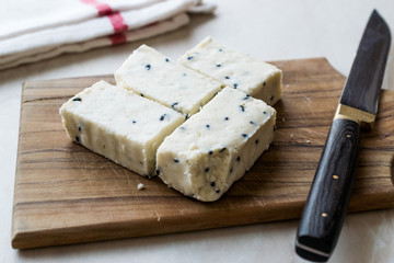 Turkish Feta Cheese with Black Cumin (Sesame) Seeds on Wooden Surface with Knife.