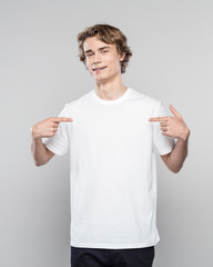 Young man in white t-shirt pointing at his chest