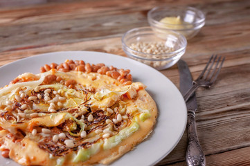 Vegetarian Omelette with fried cabbage, beans and spices on a wooden table. Healthy breakfast concept. Traditional Mediterranean cuisine. Selective focus. Low key