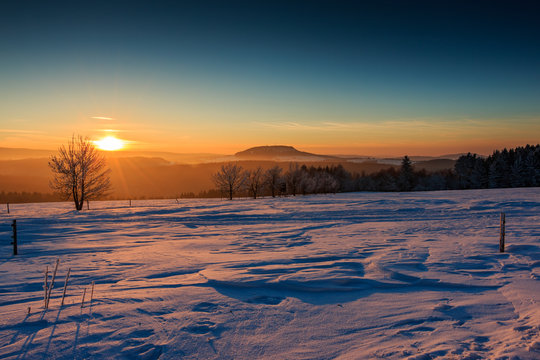 Sonnenuntergang im goldenen Sonnenlicht &uuml;ber dem winterlichen Erzgebirge. Blick zum Scheibenberg, Fichtelberg und Keilberg.