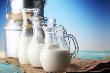 A jug of milk and glass of milk on a wooden table