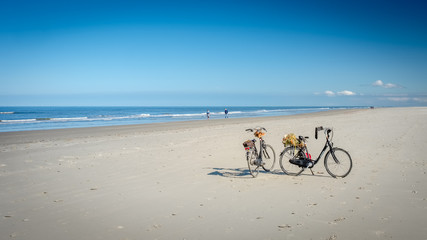 On a summer September afternoon on the beach of the Dutch Wadden Isle of Schiermonnikoog located in the Wadden Sea, two bikes are waiting for their owners.