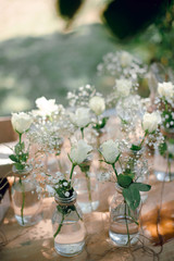 Beautiful wedding floral decoration of white roses flowers in mini-vases outdoors