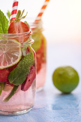Close up view on lime and strawberry detox drink in glass mason jars on a blue background 18