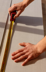 the man makes a marking with tape measure on a sheet of sound proof material, a heater