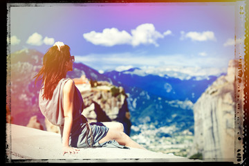 photo of the beautiful young woman sitting on the stone railing and looking at the splendid view in Greece. Image with film old frame.