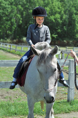Young girl riding a white horse in a helmet