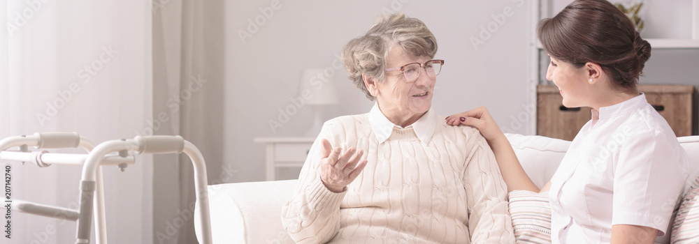 Sticker panorama of a senior woman talking to a young, female caregiver in a private rehabilitation center