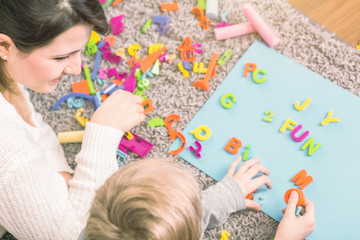 Young boy learning letters during a session with speech therapist - obrazy, fototapety, plakaty
