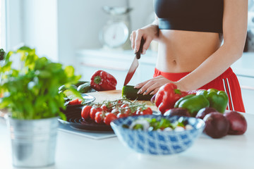 Young woman in sport clothes preparing salad in the kitchen