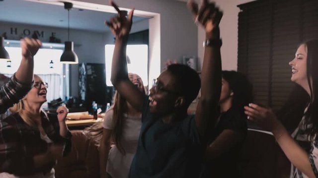 Successful African American Freelance Worker Celebrating Victory With Multiethnic Colleagues At House Party Slow Motion.