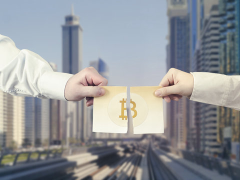 Two hands tear the paper banknote of bitcoin into two part on the background Dubai.United Arab Emirates Symbol BTC. Bitcoin bifurcation
