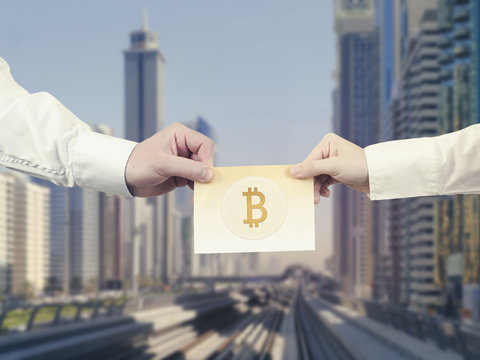 Paper banknote crypto currency of bitcoin in the hand of men and woman on the background Dubai. 