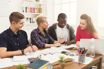 Group of diverse students studying at wooden table