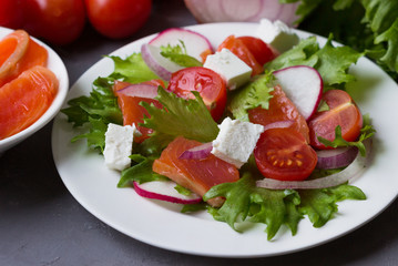 Fresh salad from salmon and vegetables on a white plate.