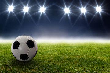 Fototapeta premium Fußball vor Strahlern auf dem Rasen im Stadion