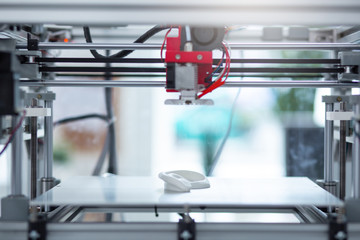 Brand new model. The close up of a state-of-the-art 3D printer creating a new 3D model while standing in the office