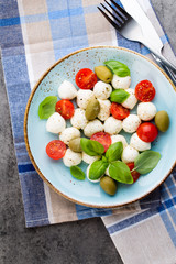 Delicious caprese salad with ripe cherry tomatoes and mini mozzarella cheese balls with fresh basil leaves.