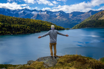 Fototapeta na wymiar guy standing on a cliff with beautiful mountain lake view