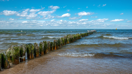 Fototapeta na wymiar spokojne morze Bałtyckie zalewa słoną wodą drewniane pale ochronne. Międzyzdroje, Polska
