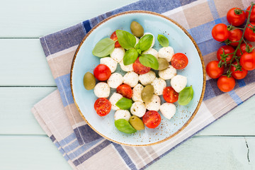 Delicious caprese salad with ripe cherry tomatoes and mini mozzarella cheese balls with fresh basil leaves.