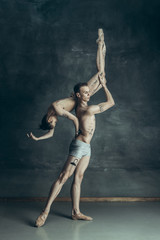 Obraz na płótnie Canvas The young modern ballet dancers posing on gray studio background