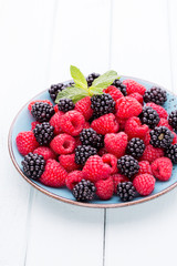 Fresh raspberries in a plate on a  vintage background.