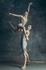 Naklejka na ściany i meble The young modern ballet dancers posing on gray studio background