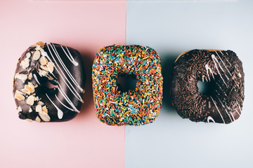 three square shape doughnut with different toppings on blue and pink background. sweet food and...