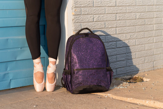 Urban Ballerina Against Blue Door Holding A Purple Backpack