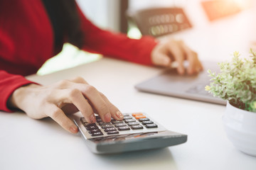 Close-up of a businesswoman hands using laptop and counting on calculator.Financial and investment concept.