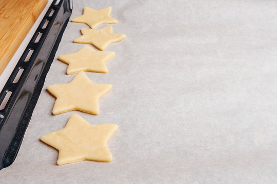 the process of making christmas cookies, raw dough, rolling pin and baking star forms.