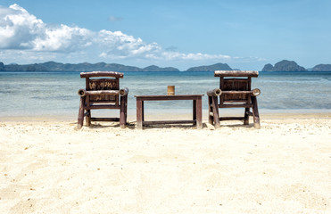 Table and chairs on an exotic beach on a hot sunny day against the blue sea and sky.