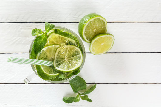 Fresh lemonade from lime or mojito with ice on a white wooden rustic background. Top view. Copy space