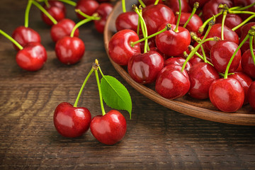 Two ripe cherries on the background of a village table, a bunch of cherries in a clay dish and scattered on a table