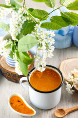 Vitaminic healthy sea buckthorn tea in metal tea cup on the white background. blooming tree branches