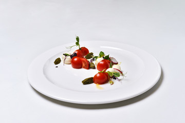 Mozzarella with tomatoes salad on a white plate isolated.