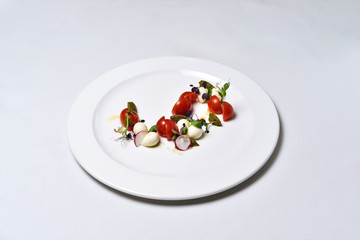 Mozzarella with tomatoes salad on a white plate isolated.