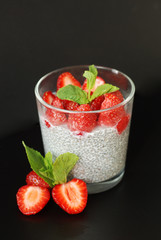 Healthy Dessert Pudding Chia Seeds in Yogurt, Yogurt and Strawberries and Mint in the Glass Bowls. Black Background.