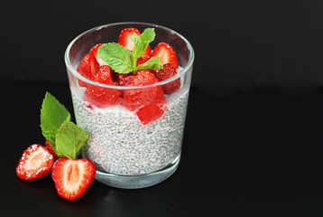 Healthy Dessert Pudding Chia Seeds in Yogurt, Yogurt and Strawberries and Mint in the Glass Bowls. Black Background.