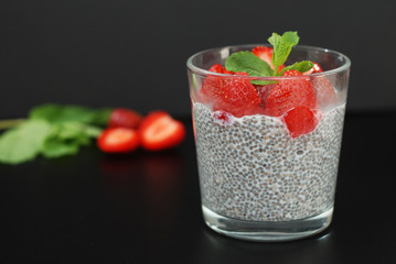 Healthy Dessert Pudding Chia Seeds in Yogurt, Yogurt and Strawberries and Mint in the Glass Bowls. Black Background.