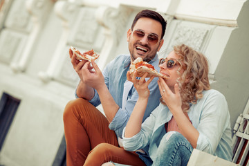 Couple eating pizza snack outdoors