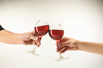 Hands with glasses of red wine, isolated on white