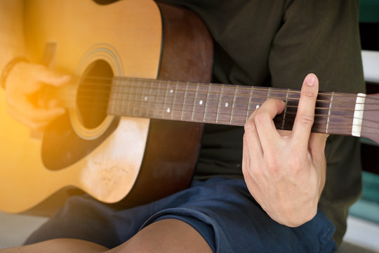 Close up soft focus and blur guitarist's hand is holding the chord B on acoustic guitar fretboard in time to relax