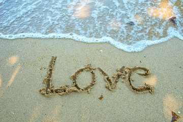 Write the word love on the beach. Soft focus wave.