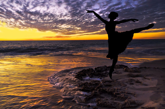 Silhouette of a ballet dancer at the beach at sunset 
